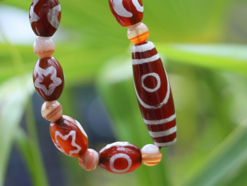 Two-eye dZi bead with Universe Dzi Bead | Sun/Moon. The sun, moon, and star painted on this Dzi bead represent this universal life energy.