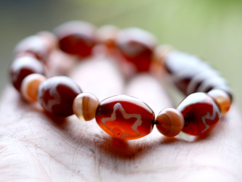 Two-eye dZi bead with Universe Dzi Bead | Sun/Moon. The sun, moon, and star painted on this Dzi bead represent this universal life energy.