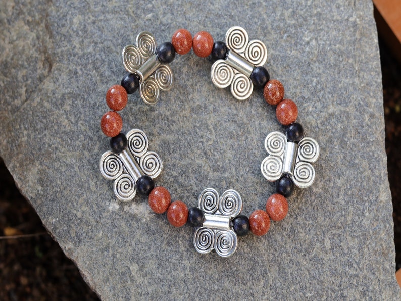 Glittering  Goldstone bracelet combined with wood and Butterfly spacers. A powerful beacon of growth and new beginnings