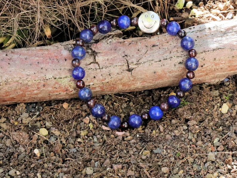 The Bāla Sagrahi Kids Collection. Children's Size Lapis Lazuli 6 mm Gemstone Bracelet with 4mm Red Garnet beads and Happy Face Bead.