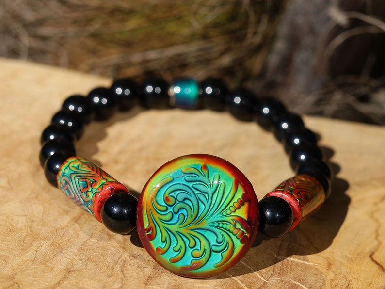 Color-changing Mirāja collection. Black Agates Carnelian bracelet with Mirage Mood Fountain Fern Coin Bead. Mirage Mood Glow Nouveau Bead.