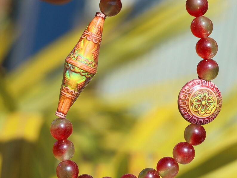 Color-changing Mirāja collection.  Watermelon Jade bracelet with Mirage Mood Bali Sunset Elongated Bicone Bead. Mirage Mood Sun Blossom Bead