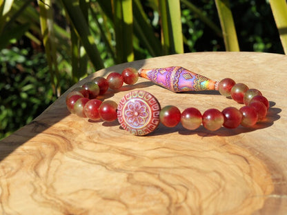 Color-changing Mirāja collection.  Watermelon Jade bracelet with Mirage Mood Bali Sunset Elongated Bicone Bead. Mirage Mood Sun Blossom Bead