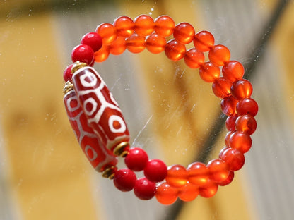 This precious Nine Eyed DZI bead is strung with natural red Carnelian. And Faceted Red Coral beads..