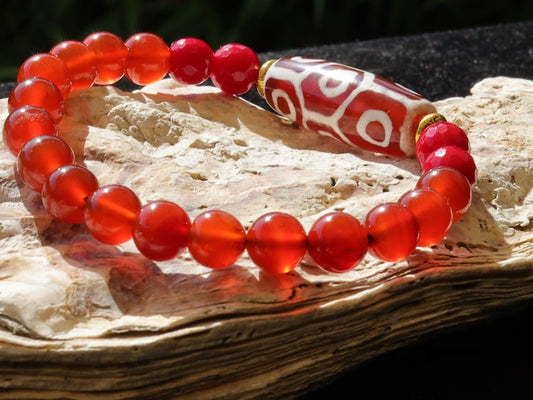 This precious Nine Eyed DZI bead is strung with natural red Carnelian. And Faceted Red Coral beads..