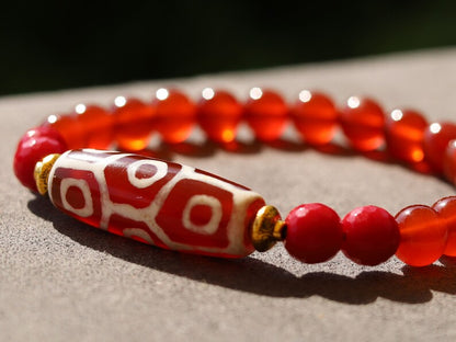 This precious Nine Eyed DZI bead is strung with natural red Carnelian. And Faceted Red Coral beads..