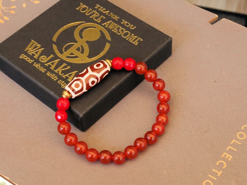 This precious Nine Eyed DZI bead is strung with natural red Carnelian. And Faceted Red Coral beads..