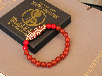 This precious Nine Eyed DZI bead is strung with natural red Carnelian. And Faceted Red Coral beads..