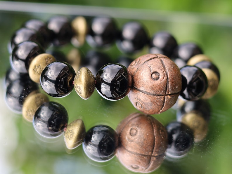 Metallook bead bronze round with dots with black agate beads. is believed to have protective and grounding properties