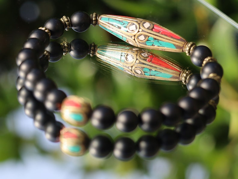 The Shaligram stones with Nepalese Brass beads from Nepal. Inlaid with turquoise and coral. Size : 25 x 10 mm