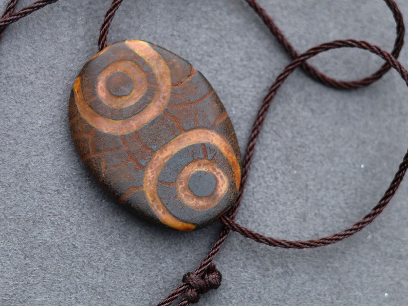 Brown Oval Flat 4 eyed Dzi Bead, Big Flat Barrel Vintage Tibetan Agate.  Overall, the four-eyed dzi bead is highly valued for its powerful protective energy and its ability to promote harmony,