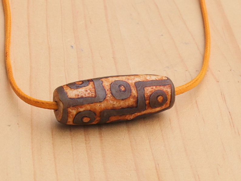 9 Eyes Dzi Bead made of brown grained relief Agate necklace.  It's believed to offer protection, promote spiritual growth, and bring harmony