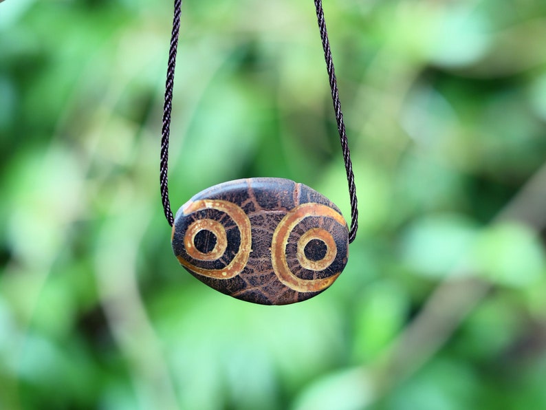 Brown Oval Flat 4 eyed Dzi Bead, Big Flat Barrel Vintage Tibetan Agate.  Overall, the four-eyed dzi bead is highly valued for its powerful protective energy and its ability to promote harmony,