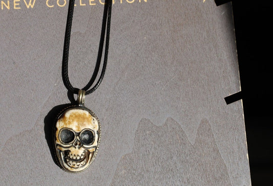 A bone skull amulet or pendant with metal mounting that originates from Nepal can hold various meanings and cultural significance.
