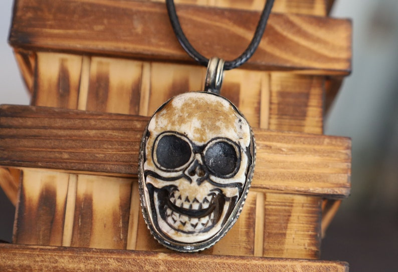 A bone skull amulet or pendant with metal mounting that originates from Nepal can hold various meanings and cultural significance.