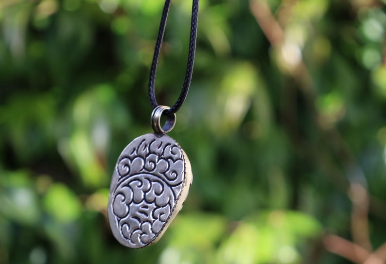 A bone skull amulet or pendant with metal mounting that originates from Nepal can hold various meanings and cultural significance.