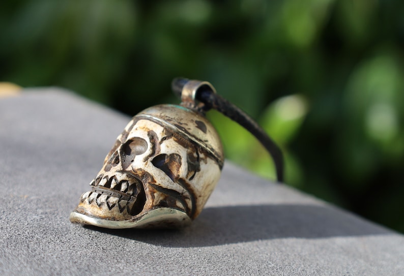 A bone skull amulet or pendant with metal mounting that originates from Nepal can hold various meanings and cultural significance.