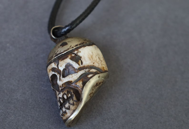 A bone skull amulet or pendant with metal mounting that originates from Nepal can hold various meanings and cultural significance.