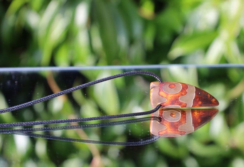 Three-eye Crescent Dzi Beads pendant necklace. In Buddhism the bead symbolizes the god of wealth Yellow Dzambala (Kubera)