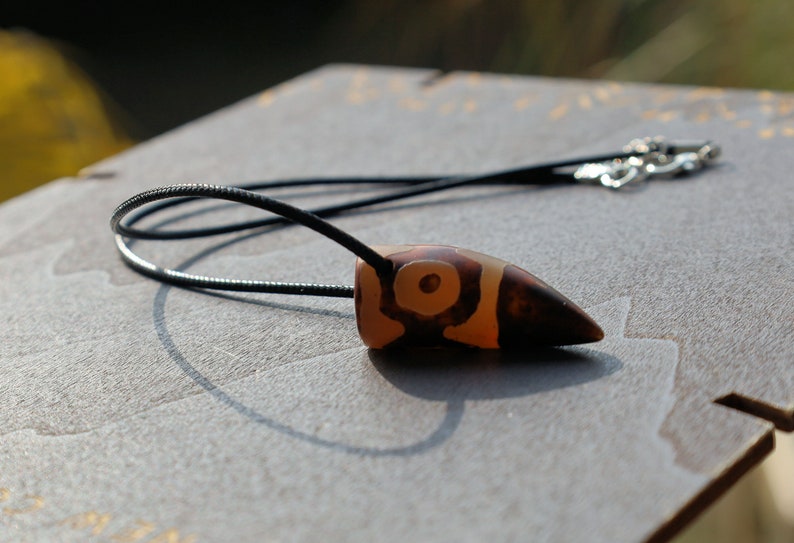 Three-eye Crescent Dzi Beads pendant necklace. In Buddhism the bead symbolizes the god of wealth Yellow Dzambala (Kubera)