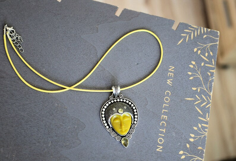 Carved Face Citrine 925, silver plated pendant. Bali Godess. Citrine, known for its captivating yellow to golden hues, embodies the warmth and energy of the sun.