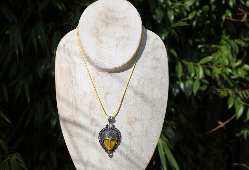 Carved Face Citrine 925, silver plated pendant. Bali Godess. Citrine, known for its captivating yellow to golden hues, embodies the warmth and energy of the sun.