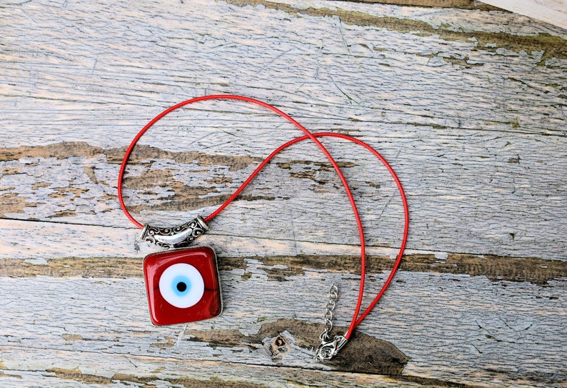 A red evil eye pendant carries with it the ancient belief in the protective power of the "evil eye," a symbol meant to ward off harm and malevolent energies directed towards the wearer.