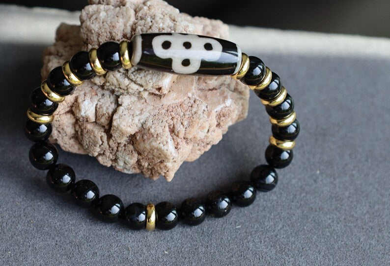 Five eyed lightning Dzi  bead with black onyx beads bracelet and Brass Spacer Beads, Rings, Golden color. Surrounded by myth and mystery
