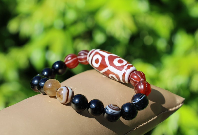 The six-eye dZi bead symbolizes luck and control, promoting health and longevity. With black striped agate 10 mm beads.  physical strength.