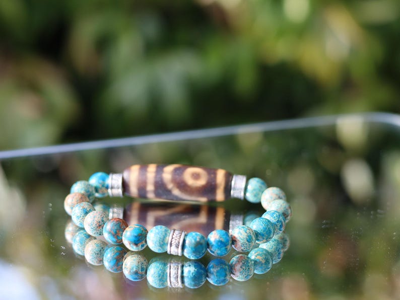 Old Two-eye dZi bead Bracelet with African Turquoise beads.  visually striking but also imbued with profound spiritual significance