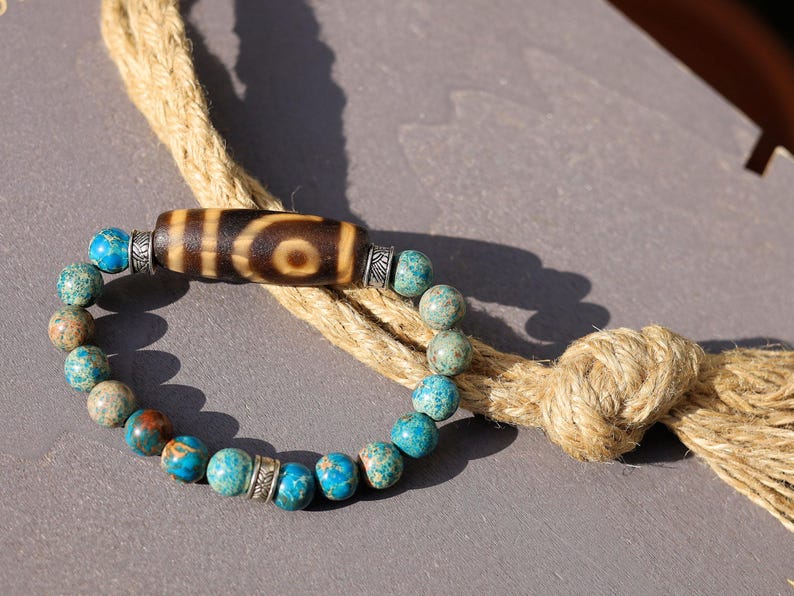 Old Two-eye dZi bead Bracelet with African Turquoise beads.  visually striking but also imbued with profound spiritual significance